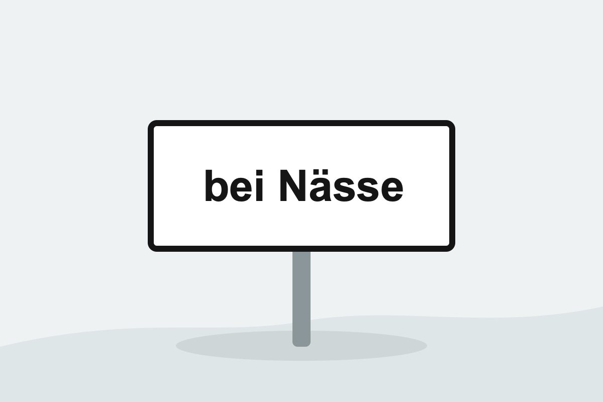 Eigenständig gezeichnetes Verkehrszeichen mit einer weißen Zusatztafel mit schwarzer Aufschrift bei Nässe.